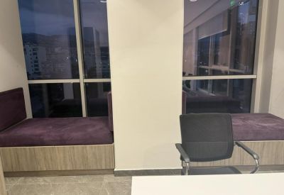 Breakout area with purple cushioned bench seating built against a large window wall.