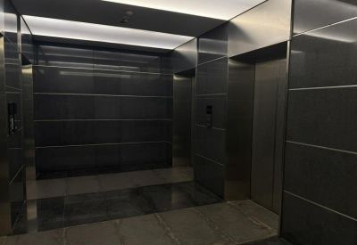 Modern elevator lobby featuring dark stone walls, silver doors, and soft cove lighting.