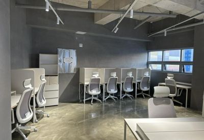 Private workstations with ergonomic chairs in a minimalist grey industrial space.