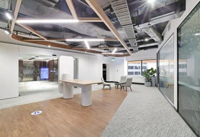 Sleek breakout area with wooden flooring, contemporary furniture, and a geometric ceiling.