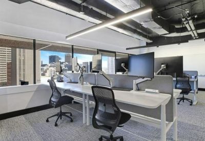 Modern workspace with ergonomic chairs, dual monitors, and large windows.