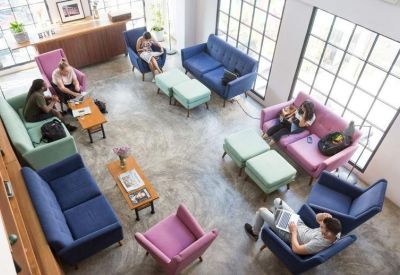 High-angle view of a bright lounge area with colourful sofas and chairs on a polished concrete floor.