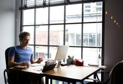 Individual workstation at a desk facing a large industrial-style window with city views.