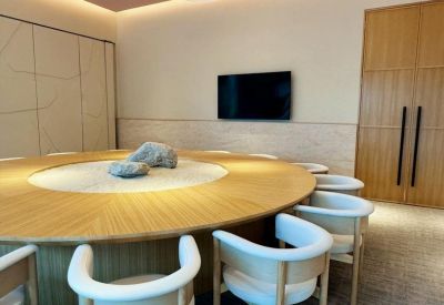 Minimalist circular boardroom table with white ergonomic chairs and a Zen rock centerpiece.