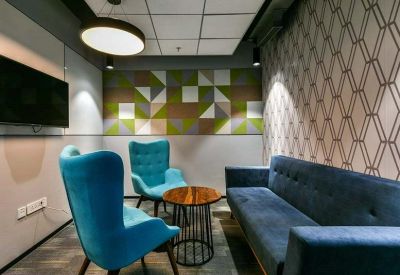Colorful breakout lounge with blue velvet armchairs, a wooden coffee table, and geometric wall art.