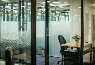 Private glass-enclosed office with a desk and ergonomic chair.