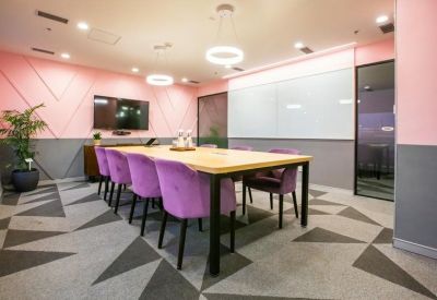 Modern meeting room with pink walls and purple velvet chairs.
