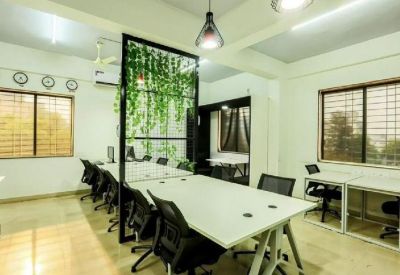 Bright office area with window-side desks and a plant-covered partition wall.