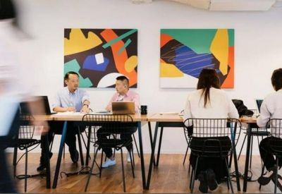 Meeting area featuring a long wooden table set against a wall with vibrant abstract artwork.