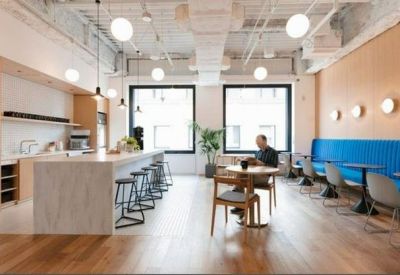 Bright kitchen and dining area with a long island, blue banquette seating, and modern pendant lighting.