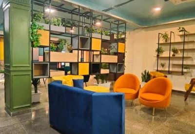 Colorful communal lounge with blue and orange tub chairs and decorative shelving.