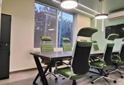 Modern meeting room featuring green-accented chairs, a dark table, and a large window.