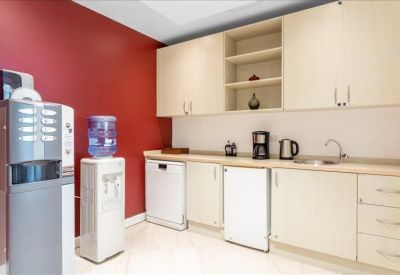 Clean communal kitchen area featuring white cabinetry, coffee station, and a bold red feature wall.