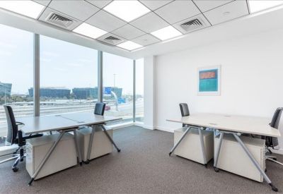Bright corner office with two modern desks and expansive floor-to-ceiling city views.