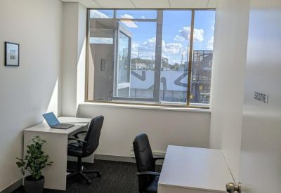 Private office with two white desks and views through a large window.