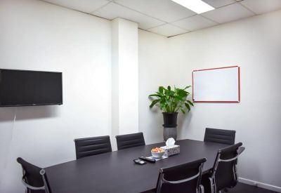 Private meeting room with a dark wood table, black chairs, and a whiteboard.