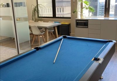 Breakout area with pool table and small dining set, natural light from large windows.