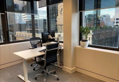 Corner office with desk, chair and city views through large windows.