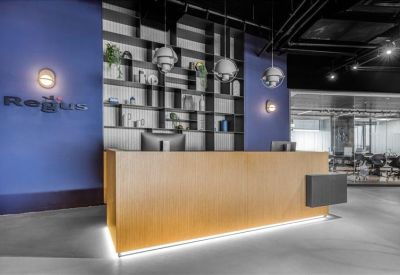 Sleek wooden reception desk backed by a blue feature wall and stylish shelving.