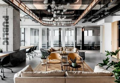 Spacious communal lounge with plush sofas, industrial ceilings, and a large decorative light fixture.