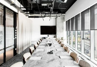 Modern boardroom with a long marble table, comfortable tan chairs, and city views through large windows.