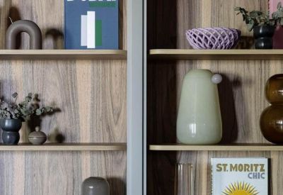Close-up of wooden shelving units styled with books and various decorative ceramic vases.
