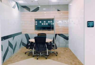Small private meeting room with a round table, ergonomic chairs, and geometric wall patterns.