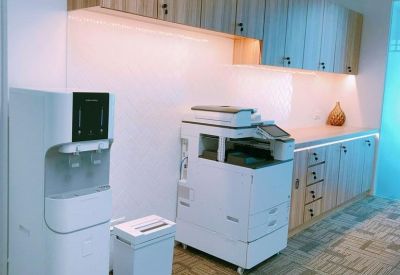 Office utility area featuring a water dispenser, printer station, and light wood cabinetry.