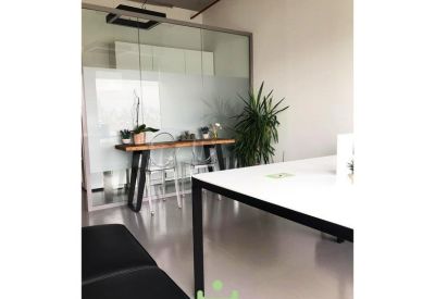 Contemporary breakout area featuring a wooden bar table, green plant, and glass partitions.