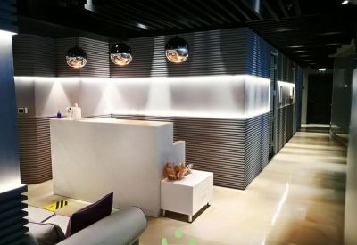 Minimalist reception area with a white desk, warm feature lighting, and dark slat walls.