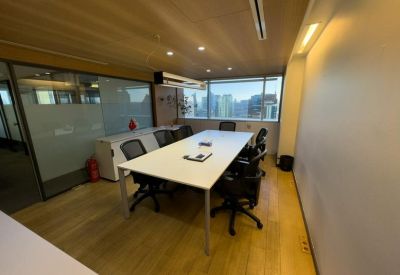 Meeting room with a white table, black chairs, and a large window.