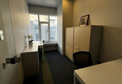 Compact private office with a desk, chair, and storage cabinets by a window.