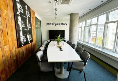 Bright conference room with a large oval table, wood-paneled wall, and city views.