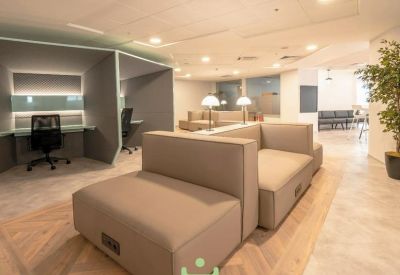 Modern lounge area featuring plush tan sofas and private semi-enclosed workstations.