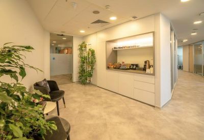 Bright office reception area with a coffee bar, seating, and lush green plants.