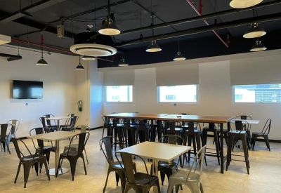 Modern communal dining area with industrial lighting, wooden tables, and metallic chairs.