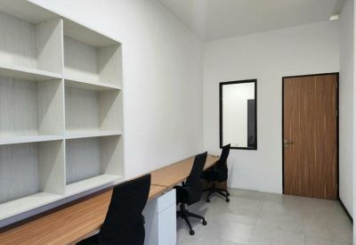 Long wooden workbench in a shared office space with a large built-in white bookshelf.