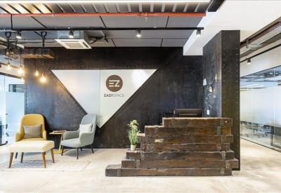 Stylish reception desk made of dark wood planks with comfortable lounge seating nearby.