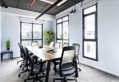Bright conference room with a wooden table, ergonomic black chairs, and large windows.