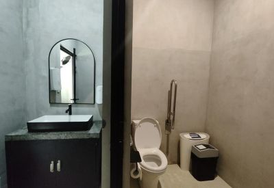 Modern industrial-style bathroom featuring a black vanity and minimalist grey walls.