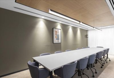 Sleek conference room featuring a long white table and gray chairs under a wood-paneled ceiling.
