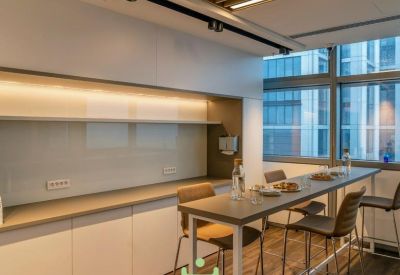 Modern communal kitchen area with high stools and city views.