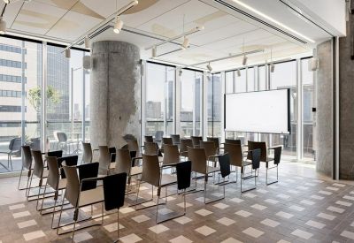 Sunlit seminar room with neat rows of chairs and a large projector screen.