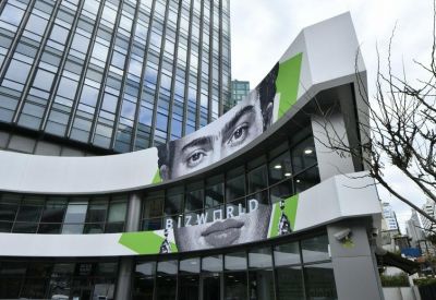 Modern exterior facade of Olive Plaza featuring a curved glass front and large monochrome artistic portrait.