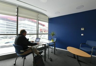 Private office suite with a blue accent wall, minimalist desk, and views over a city square.