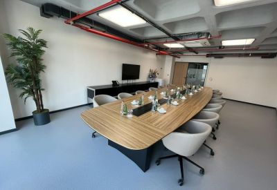 Large conference table with several grey chairs and a potted plant.