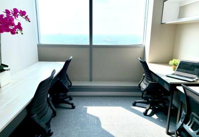 Bright office space with white desks, ergonomic black chairs, and floor-to-ceiling window views.