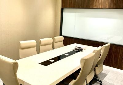 Professional meeting room featuring a long white table and executive cream-colored chairs.