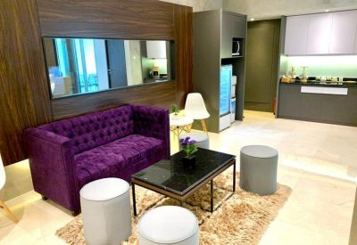 Close-up of a stylish purple tufted sofa in a lounge with a wood-paneled feature wall.