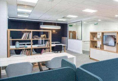 Modern breakout area with wooden shelving, comfortable seating, and blue acoustic partitions.